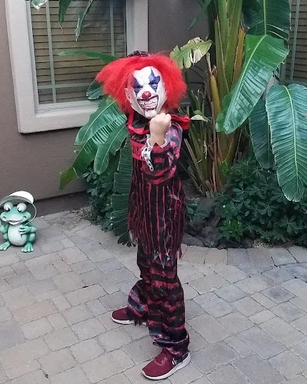 A child in a red-haired clown costume striking a pose on Halloween